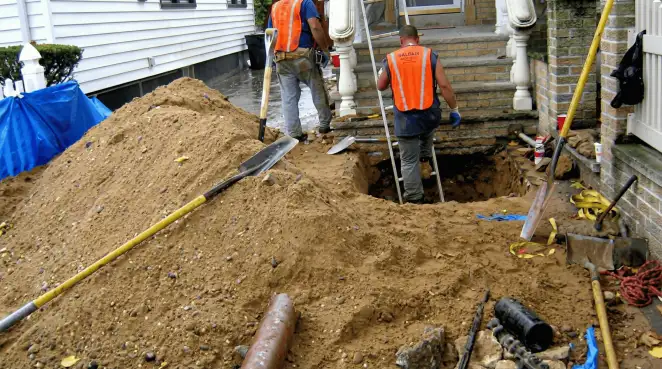 Contractors performing foundation protection and exterior drainage excavation near residential home steps in Phoenix, AZ