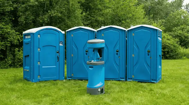 Four blue portable toilets and a matching hand washing station on grass near trees, a common sight at local outdoor events in Phoenix, AZ