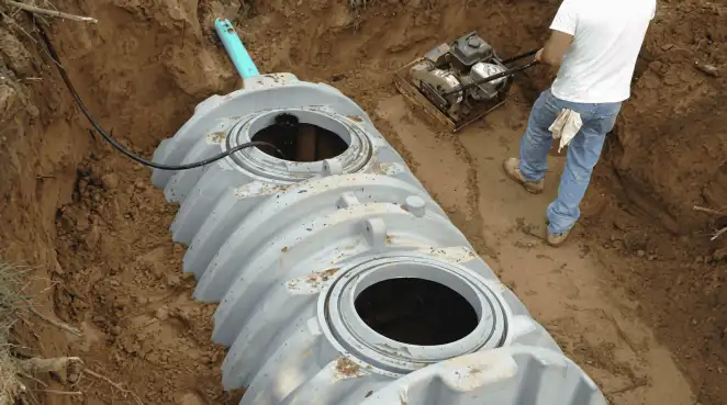 Septic tank installation showing a technician compacting soil around a new poly septic tank in an excavation pit in Phoenix, AZ